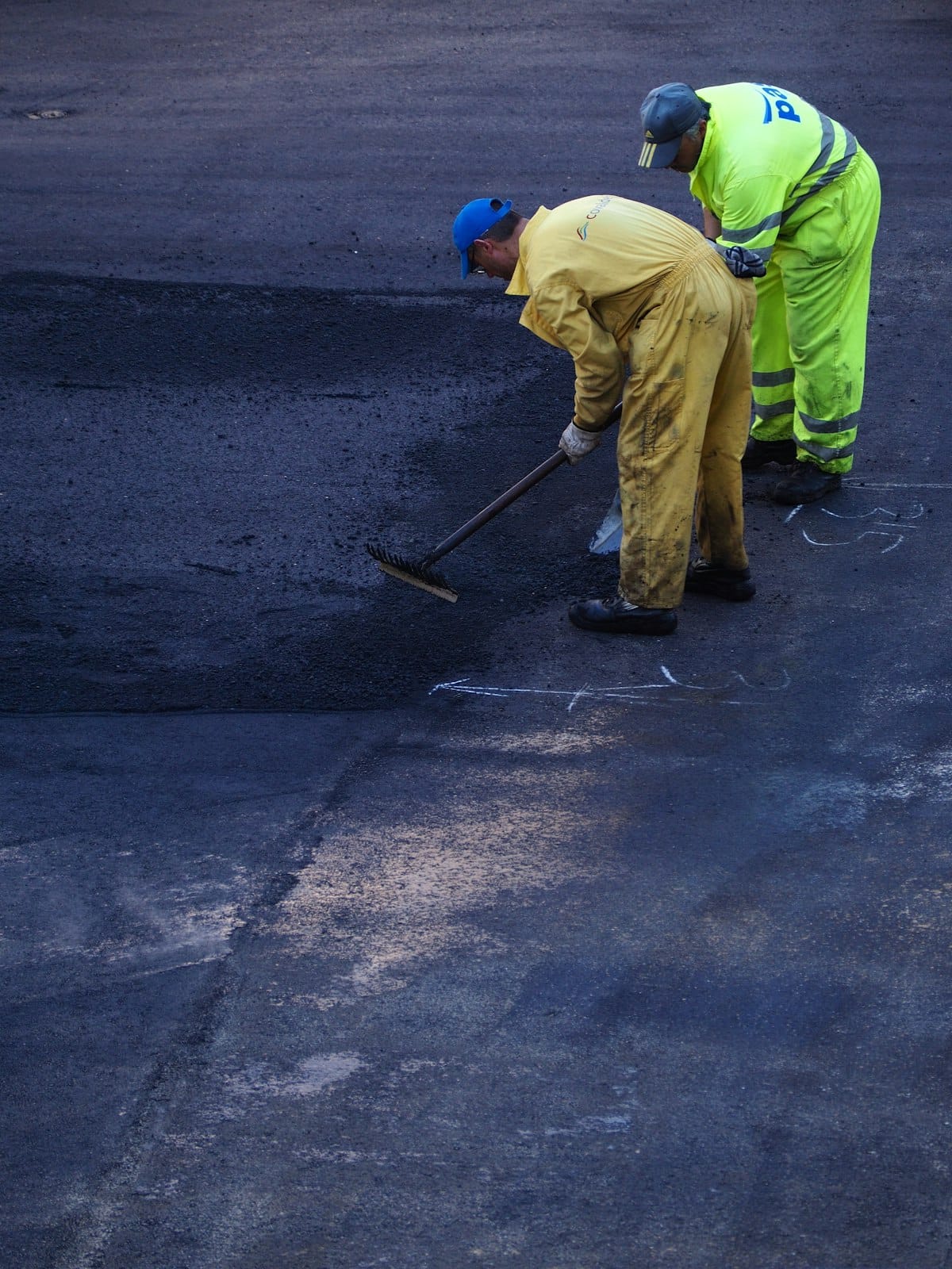Road maintenance crew resurfacing a damaged road